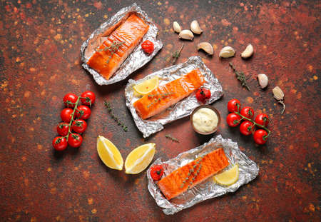 Foil with cooked salmon fillet on color backgroundの写真素材