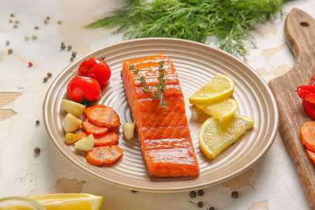 Plate with cooked salmon fillet and vegetables on table