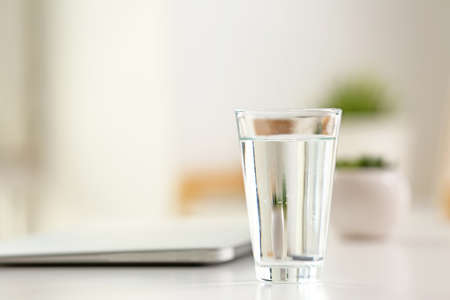 Glass of water with laptop on workplace in officeの写真素材