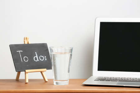 Glass of water with laptop on workplace in office