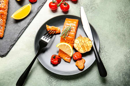 Plate with cooked salmon fillet and vegetables on color backgroundの写真素材