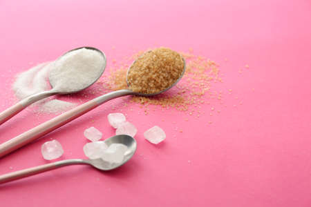 Spoons with sweet sugar on color background