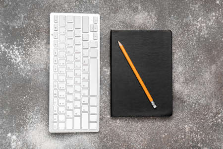 Notebook, ordinary pencil and PC keyboard on gray background