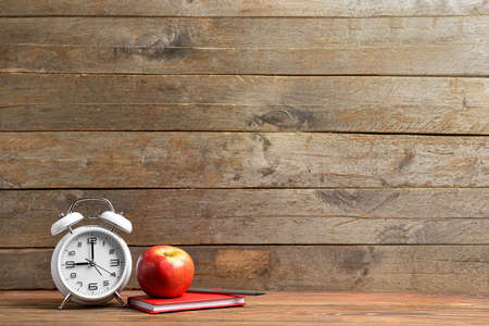 School supplies, apple and clock on table. Time to studyの写真素材