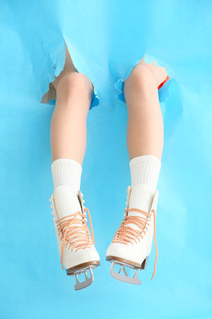 Young woman in ice skate shoes tearing color paperの写真素材