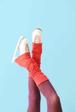 Young woman in ice skate shoes on color background