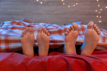 Feet of young couple sleeping in bed at night