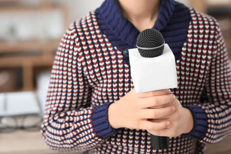 Little journalist with microphone having an interview in office, closeup