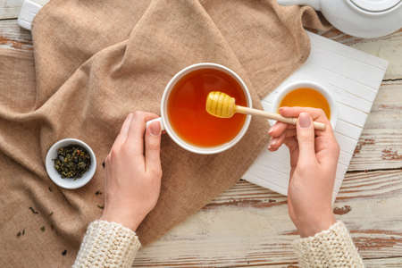 Woman drinking tea with honey at table, top viewの写真素材