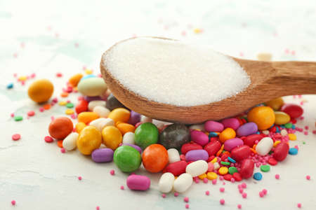 Spoon with sweet sugar and candies on white backgroundの写真素材