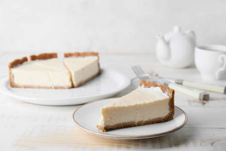 Plates with pieces of sweet tasty cheesecake on table