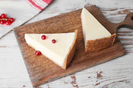 Pieces of sweet tasty cheesecake and red currant on table