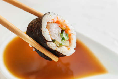 Dipping of tasty sushi roll into soy sauce, closeupの写真素材