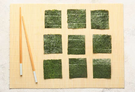 Tasty seaweed sheets and chopsticks on bamboo matの写真素材