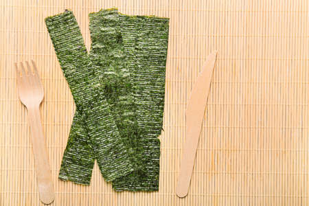 Tasty seaweed sheets, fork and knife on bamboo matの写真素材