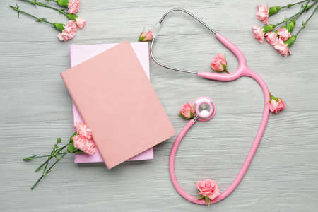 Stethoscope with flowers and notebooks on wooden backgroundの写真素材
