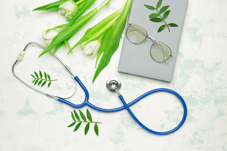 Stethoscope with flowers and notebook on white backgroundの写真素材