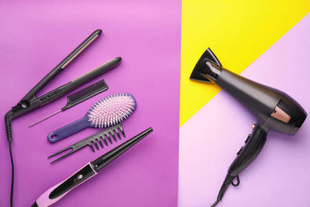 Modern blow dryer and hairdresser tools on color backgroundの写真素材