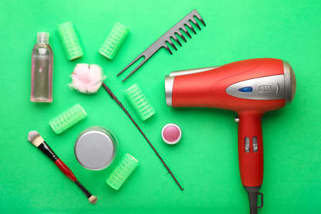 Modern blow dryer and hairdresser tools on color background