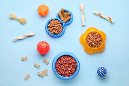 Bowls with pet food and toys on color backgroundの写真素材