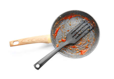 Dirty empty frying pan with shovel on white background