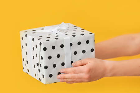 Female hands with beautiful gift box on color backgroundの写真素材