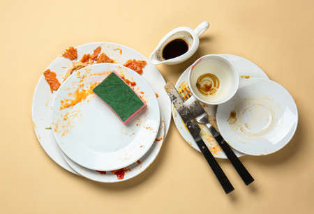 Dirty empty dishes with sponge on color backgroundの写真素材