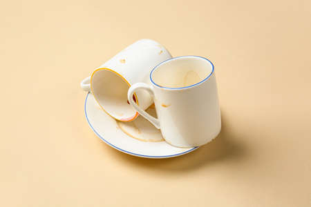 Dirty empty cups with plate on color background