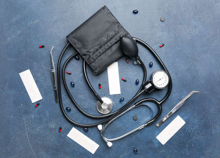 Stethoscope with sphygmomanometer and pills on dark background