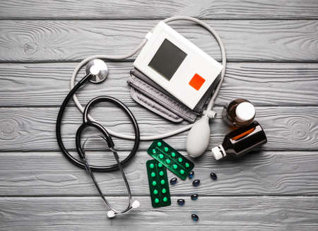 Stethoscope with sphygmomanometer and pills on wooden backgroundの写真素材