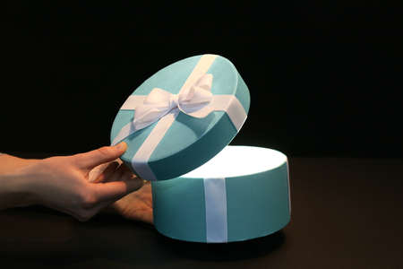 Female hands with beautiful gift box on dark background
