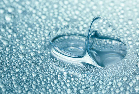 Contact lenses and water drops on color background