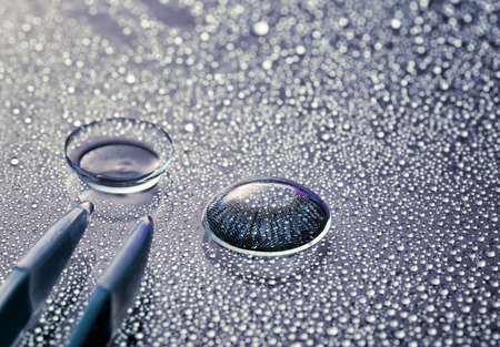 Contact lenses, tweezers and water drops on gray background, closeupの写真素材