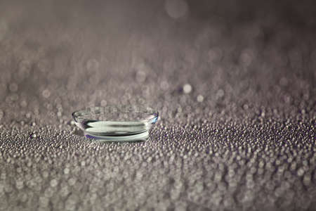Contact lens and water drops on gray backgroundの写真素材