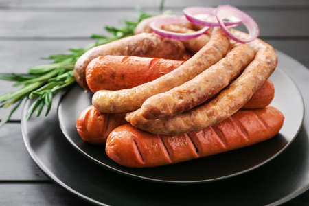 Plate with tasty grilled sausages on tableの写真素材