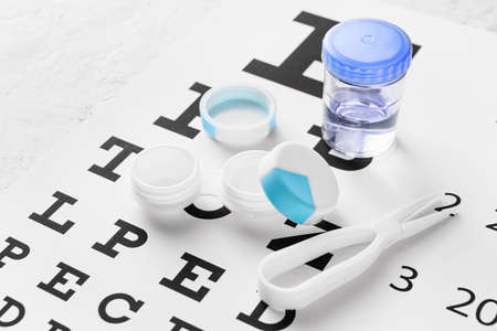 Container with contact lenses and tweezers on eye test chart, closeupの写真素材