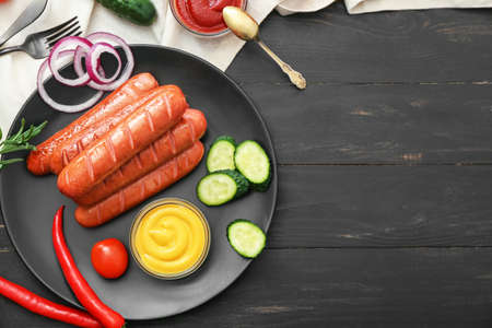 Plate with tasty grilled sausages, vegetables and sauce on tableの写真素材