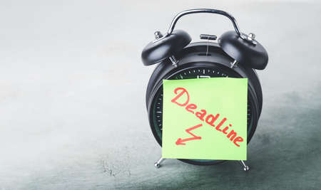 Alarm clock and paper with text DEADLINE on tableの写真素材