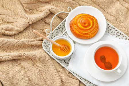 Tasty honey with bun and cup of tea on trayの写真素材