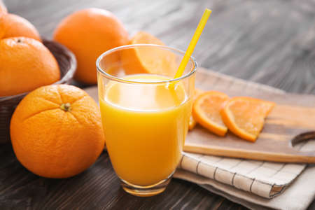 Glass of fresh orange juice and fruit on table