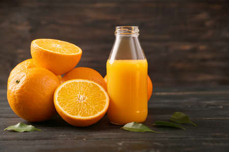 Bottle of fresh orange juice and fruit on wooden backgroundの写真素材