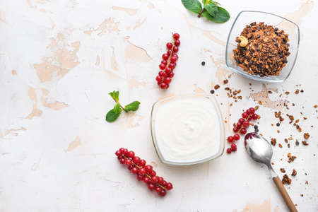 Bowls with tasty yogurt, granola and berries on white backgroundの写真素材