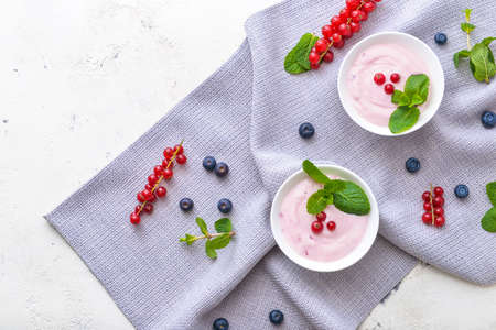Bowls with tasty yogurt and berries on white backgroundの写真素材