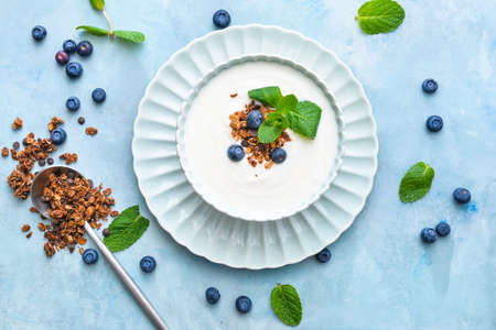 Bowl with tasty yogurt, granola and berries on color backgroundの写真素材