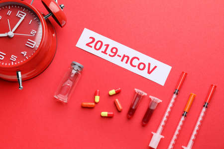 Test tubes with blood sample, medicines for Coronavirus and alarm clock on color backgroundの写真素材
