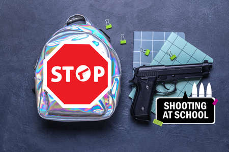 School backpack with gun and stationery on dark background. Problem of shooting at schoolの写真素材