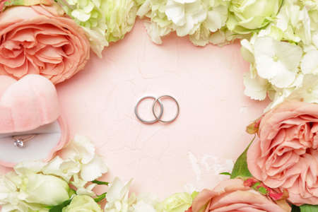 Beautiful wedding rings with flowers on color backgroundの写真素材