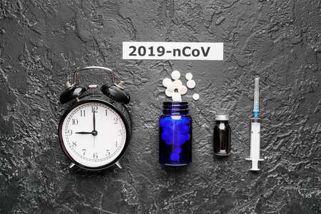 Alarm clock and medicines for Coronavirus on dark backgroundの写真素材