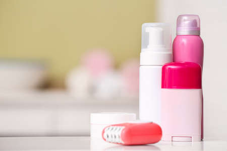 Modern epilator with cosmetics on table in bathroom