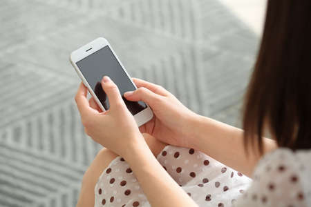 Beautiful young woman with mobile phone at home, closeupの写真素材